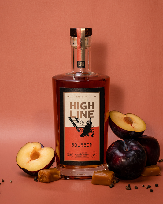 Bottle of High Line Bourbon with plums and caramels on a coral colored background