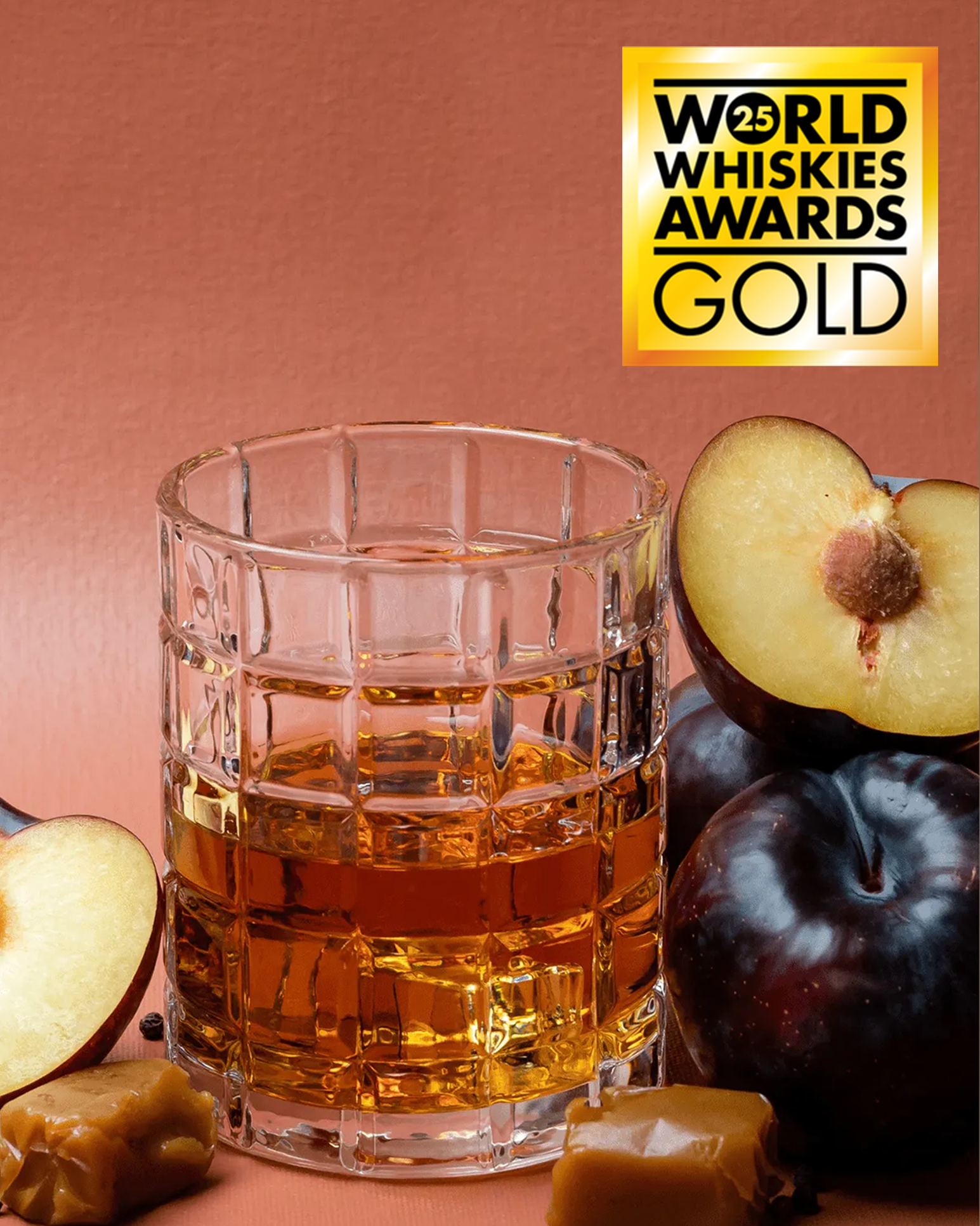 Glass of whiskey with fruits on a brown background, featuring the World Whiskies Awards Gold logo.