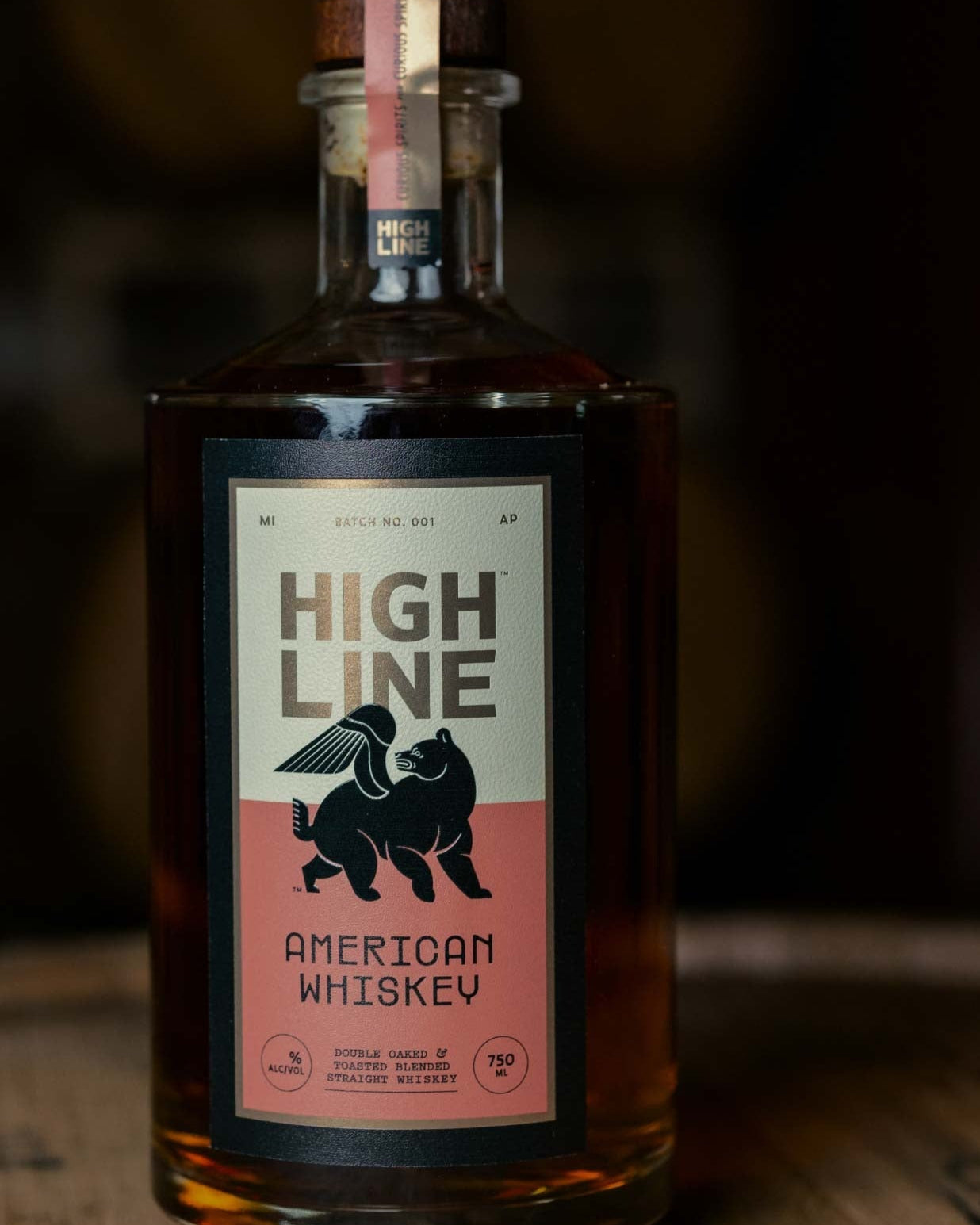Bottle of High Line American Whiskey on a wooden surface with a dark background
