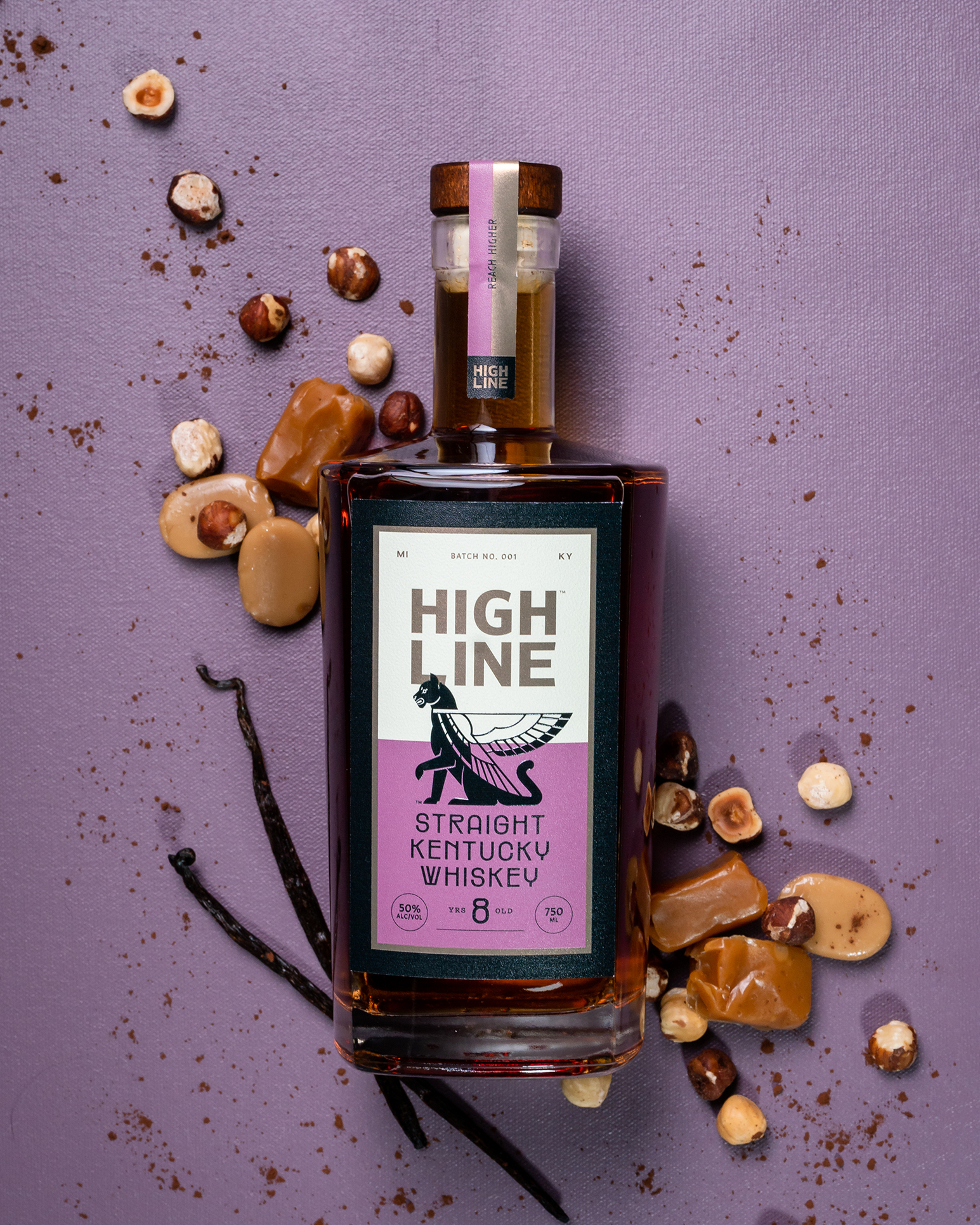 Bottle of High Line Straight Kentucky Whiskey with nuts and vanilla bean on a purple background